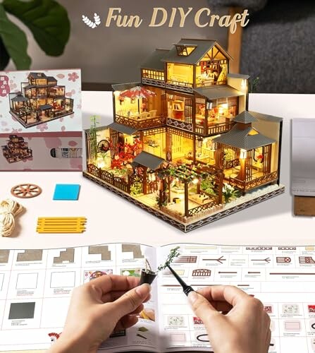 Hands assembling a DIY miniature house with lights and detailed interior.