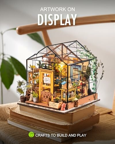 Miniature greenhouse model displayed on books.