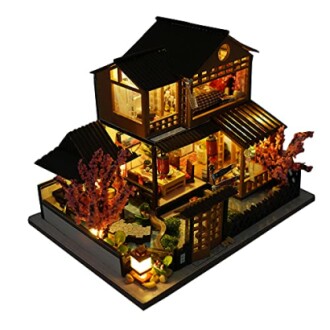 Illuminated miniature Japanese-style dollhouse with cherry blossoms.